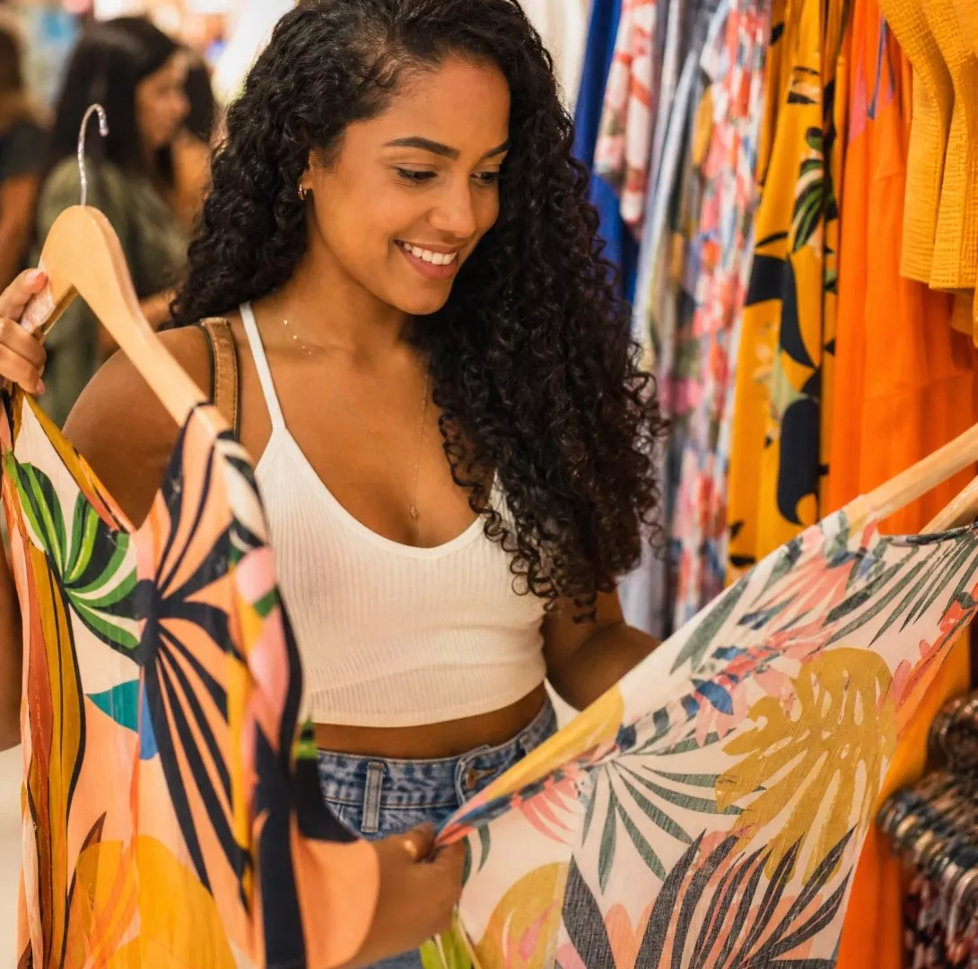 Mulher sorrindo escolhendo roupas em uma loja